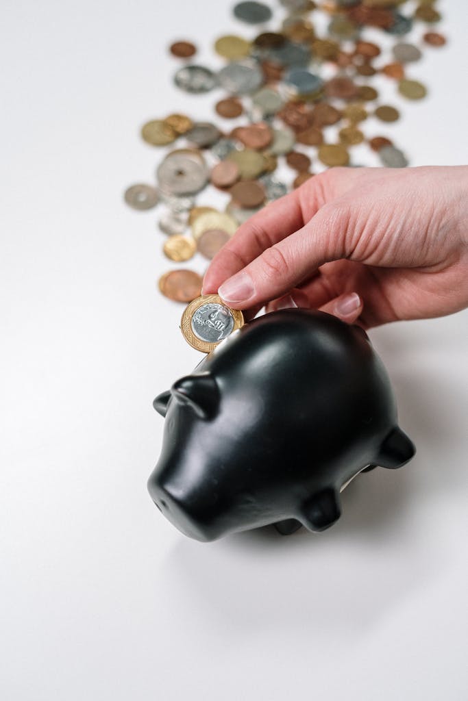 Person Putting Coin in a Piggy Bank
